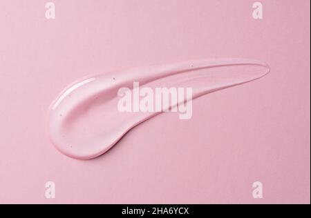 Transparenter Geltropfen auf rosa Hintergrund. Flüssiges Gel kosmetische Fleck Textur. Beauty-Serumtropfen. Transparente Hautpflegeproduktprobe. Stockfoto