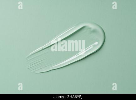 Transparenter Geltropfen auf grünem Hintergrund. Flüssiges Gel kosmetische Fleck Textur. Beauty-Serumtropfen. Transparente Hautpflegeproduktprobe. Stockfoto