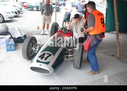 Die Schwester von Bruce McLaren, Jan, sitzt neben dem „Slimline“ Cooper T70, der von Bruce und Wally Wilmott entwickelt wurde, um 1964 die Tasman Series zu bestreiten. Die kürzeren Rennen ermöglichten es Bruce und Wally, das Auto zu erleichtern und einen Kraftstofftank unter dem Sitz zu positionieren und auch das Chassis zu steifen. Das Fahrzeug ist mit einem 4-Zylinder-2,5-Liter-Coventry-Climax-Motor ausgestattet. Das Auto wurde bei der offiziellen Eröffnung der Hampton Downs-Rennstrecke in North Waikato, etwa auf halbem Weg zwischen Auckland und Hamilton, beim NZ Festival of Motor Racing, das Bruce McLaren im Januar 22nd 2010 feierte, ausgestellt. Stockfoto