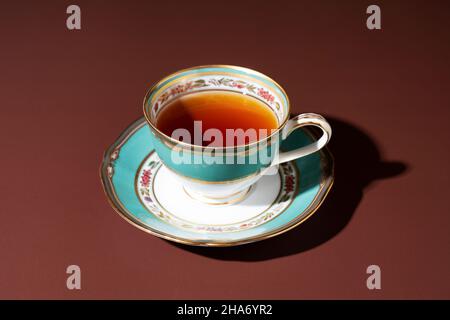 Heißer Tee in einer eleganten Tasse und Untertasse vor braunem Hintergrund. Stockfoto