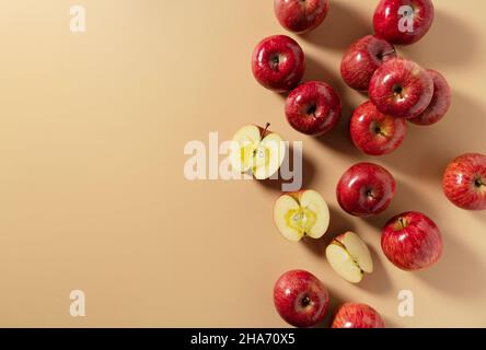 Eine Menge Äpfel auf beigem Hintergrund gelegt, in zwei Hälften oder Viertel geschnitten. Komposition von oben gesehen. Stockfoto