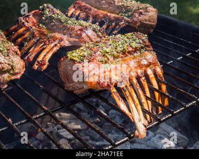 Racks mit Lammfleisch auf dem Grillrost, gebräunt mit Kräutern Stockfoto