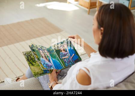 Frau schaut durch Bilder von Schwangerschaft Fotoshooting in schönen Fotobuch Stockfoto