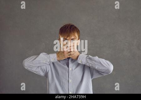 Geheimnis, Stille Konzept. Nahaufnahme eines jungen Mannes in einem grauen Hemd Stockfoto