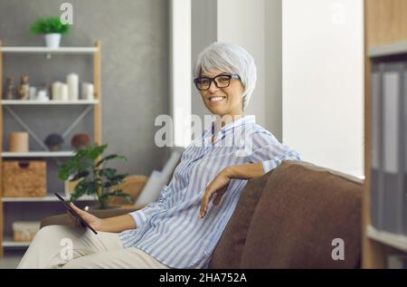 Porträt einer lächelnden Frau mittleren Alters Verwenden Sie Tablet Stockfoto