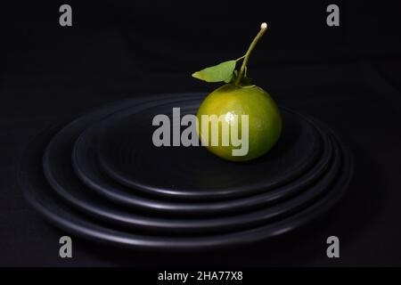 Grüne Mandarine auf schwarzem Hintergrund Stockfoto