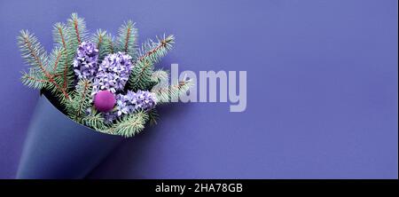 Winter Panorama Banner mit Blumenstrauß auf lila sehr peri monochromen Papier Hintergrund. Tannenzweige und blaue Hyazinthen. Einfache minimale Winetrtime Stockfoto