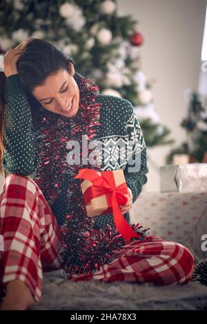 Schöne kaukasische Frau, die an einem Weihnachtsmorgen Geschenke eröffnet Stockfoto