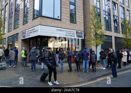 Vor Rough Trade in Bristol stehen Menschen Schlange, wo ein T-Shirt des Straßenkünstlers Banksy verkauft wird, um vier Personen zu unterstützen, die vor Gericht gestellt werden, weil sie wegen des Abstürzens einer Statue des Sklavenhändlers Edward Colston angeklagt sind. Bilddatum: Samstag, 11. Dezember 2021. Stockfoto