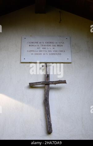 Kleines Holzkreuz an der Fassade einer Bergkirche Stockfoto