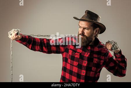 Cowboy Mann mit Bart und Schnurrbart ziehen Stahlkette, Routine auf Ranch Stockfoto