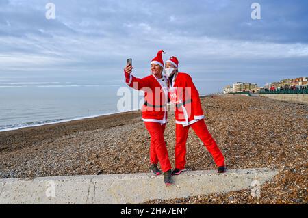 Brighton UK 11th December 2021 - Zeit für ein Selfie am Strand, bevor Sie an der diesjährigen Brighton Santa Dash on Hove Seafront teilnehmen, die Geld für die Rockinghorse Charity sammelt : Credit Simon Dack / Alamy Live News Stockfoto