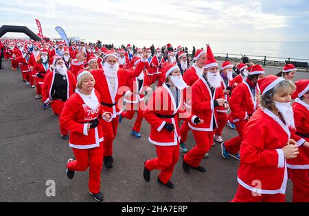 Brighton UK 11th December 2021 - Hunderte von Läufern nehmen in diesem Jahr an Brighton Santa Dash an der Küste von Hove Teil, das Geld für die Rockinghorse-Wohltätigkeitsorganisation sammelt : Credit Simon Dack / Alamy Live News Stockfoto