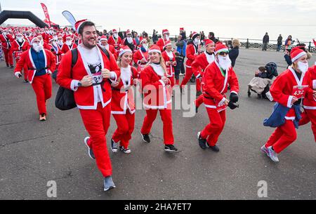 Brighton UK 11th December 2021 - Hunderte von Läufern nehmen in diesem Jahr an Brighton Santa Dash an der Küste von Hove Teil, das Geld für die Rockinghorse-Wohltätigkeitsorganisation sammelt : Credit Simon Dack / Alamy Live News Stockfoto