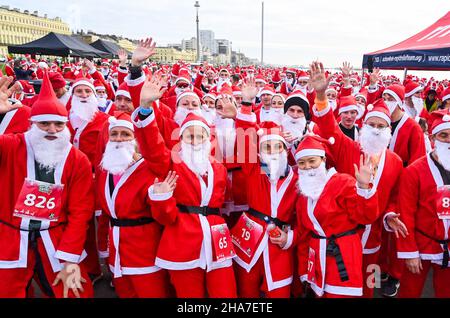 Brighton UK 11th December 2021 - Hunderte von Läufern nehmen in diesem Jahr an Brighton Santa Dash an der Küste von Hove Teil, das Geld für die Rockinghorse-Wohltätigkeitsorganisation sammelt : Credit Simon Dack / Alamy Live News Stockfoto