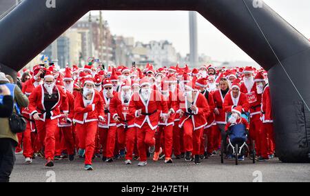 Brighton UK 11th December 2021 - Hunderte von Läufern nehmen in diesem Jahr an Brighton Santa Dash an der Küste von Hove Teil, das Geld für die Rockinghorse-Wohltätigkeitsorganisation sammelt : Credit Simon Dack / Alamy Live News Stockfoto