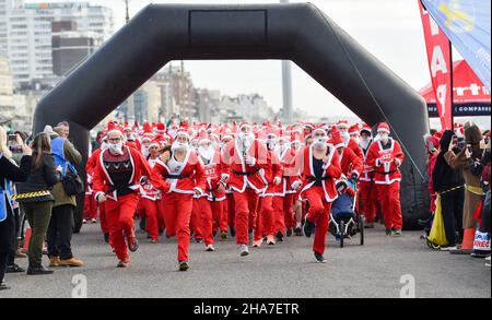 Brighton UK 11th December 2021 - Hunderte von Läufern nehmen in diesem Jahr an Brighton Santa Dash an der Küste von Hove Teil, das Geld für die Rockinghorse-Wohltätigkeitsorganisation sammelt : Credit Simon Dack / Alamy Live News Stockfoto