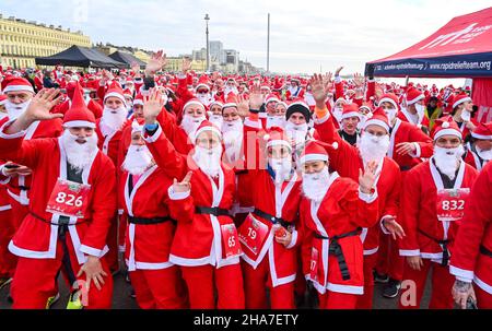 Brighton UK 11th December 2021 - Hunderte von Läufern nehmen in diesem Jahr an Brighton Santa Dash an der Küste von Hove Teil, das Geld für die Rockinghorse-Wohltätigkeitsorganisation sammelt : Credit Simon Dack / Alamy Live News Stockfoto