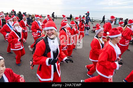 Brighton UK 11th December 2021 - Hunderte von Läufern nehmen in diesem Jahr an Brighton Santa Dash an der Küste von Hove Teil, das Geld für die Rockinghorse-Wohltätigkeitsorganisation sammelt : Credit Simon Dack / Alamy Live News Stockfoto