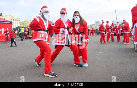 Brighton UK 11th December 2021 - Hunderte von Läufern bereiten sich auf die Teilnahme an der diesjährigen Brighton Santa Dash on Hove Seafront vor, die Geld für die Rockinghorse-Wohltätigkeitsorganisation sammelt : Credit Simon Dack / Alamy Live News Stockfoto