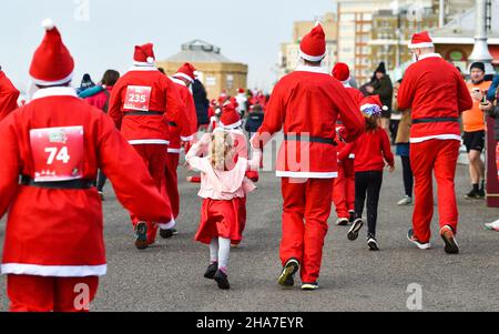 Brighton UK 11th December 2021 - Hunderte von Läufern nehmen in diesem Jahr an Brighton Santa Dash an der Küste von Hove Teil, das Geld für die Rockinghorse-Wohltätigkeitsorganisation sammelt : Credit Simon Dack / Alamy Live News Stockfoto