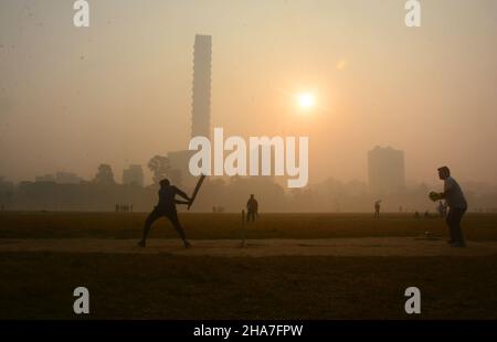 Kalkutta, Westbengalen, Indien. 11th Dez 2021. Mit dem Eintreffen des Winters ist auch die Umweltverschmutzung gestiegen. Heute war es im Winter rauchig und neblig.die boyes spielten am Wintermorgen auf dem Spielplatz Cricket.mit einem höheren Verschmutzungsgrad am frühen Morgen, Ärzte sagten, dass Menschen mit Beschwerden wie COPD und Asthma auf den Sonnenaufgang warten sollten, wenn sie einen Morgenspaziergang machen wollen.die wechselnde Jahreszeit, schwankende Temperaturen, Nebel und die steigende Umweltverschmutzung könnten eine Reihe von Gesundheitsprobleme verursachen, wenn wir keine Vorsorgemaßnahmen ergreifen. (Bild: © Rahul Sadhukhan/Pacific Press via Stockfoto