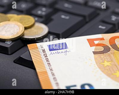 Euro-Geldschein und Münzen auf der Tastatur des Computers, Nahaufnahme, Konzeptbild des Online-Banking Stockfoto