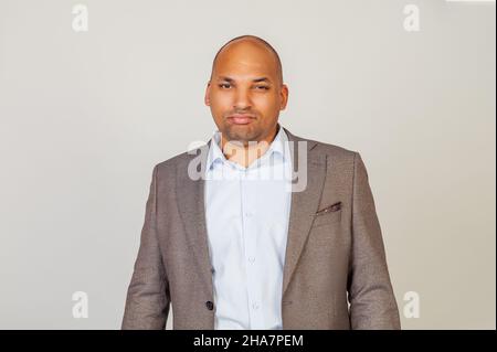 Afroamerikanischer Mann, der ernsthaft in die Kamera blickt. Geschäftsmann im klassischen Anzug, der auf die Kamera schaut, während er darauf steht Stockfoto