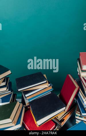 Stapel alter Bücher zum Lernen in der Bibliothek auf grünem Hintergrund Stockfoto