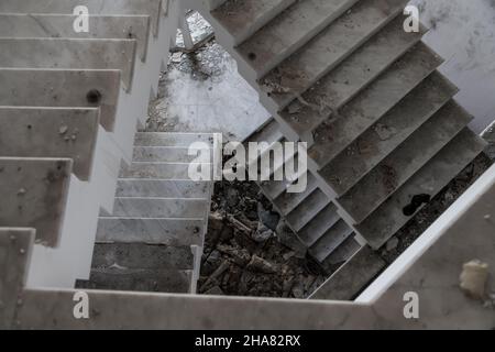 Eine alte Treppe in einem verlassenen Haus mit einem von Vandalen zerstörten Innenraum Stockfoto