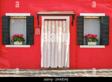 Traditioneller, farbenfroher Hauseingang mit zwei Fenstern auf der Insel Burano in Venedig Stockfoto