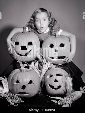 1950S KLEINES MÄDCHEN STEHT ÜBER VIER GESCHNITZTEN HALLOWEEN KÜRBISSEN JACK-O-LATERNEN MIT VERÄNGSTIGTEN GESICHTSAUSDRUCK BLICK AUF DIE KAMERA - H2948 DEB001 HARS STUDIO SCHUSS HAUS LEBEN KOPIEREN RAUM UMARMUNG ANGST SYMBOLE AUSDRÜCKE B&W AUGENKONTAKT ANGST KOPF UND SCHULTERN ÄNGSTLICHE KÜRBISSE AUFREGUNG GESCHNITZTES KONZEPT KONZEPTUELL BEDROHT ÄNGSTLICH UNLOCKER DEB001 JACK-O-LATERNEN OKTOBER SYMBOLISCHE KONZEPTE JUGENDLICHE OKTOBER 31 HERBSTLICHER SCHWARZ-WEISSER KAUKASISCH ETHNISCHE ZUGEHÖRIGKEIT ALTMODISCHE DARSTELLUNG Stockfoto