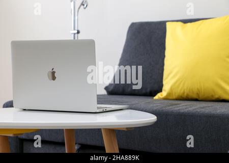 Arbeiten von zu Hause pic, öffnen Macbook Pro Laptop auf weißem Tisch durch leere graue Sofa mit gelben Kissen Stockfoto