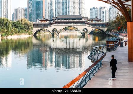 Älterer Mann praktiziert Tai Chi am Jinjiang Fluss mit Blick auf die ikonische Anshun Brücke in Chengdu, einer Megastadt in Sichuan, China - bekannt für ihre RE Stockfoto