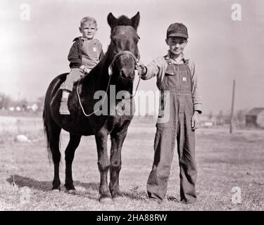 1930S BAUERNJUNGE, DER EIN SCHWARZES PONY-PFERD FÜHRT, WOBEI SEIN KLEINER BRUDER BARBACK SITZT UND SOWOHL OVERALLS TRÄGT ALS AUCH ANSCHAUT KAMERA - H6706 HAR001 HARS JUGENDLICH GESICHTSSTIL PFERDE TEAMWORK STARK ERFREUT FREUDE LIFESTYLE BRÜDER LÄNDLICHEN HEIM LEBEN KOPIEREN RAUM FREUNDSCHAFT HALBE LÄNGE INSPIRATION FÜRSORGLICH LANDWIRTSCHAFT MÄNNCHEN PONY GESCHWISTER VERTRAUEN TRANSPORT AUSDRÜCKE FÜHREN LANDWIRTSCHAFT B&W FREIHEIT ZIELE ERFOLG GLÜCK SÄUGETIERE FRÖHLICH SEINE UND BAUERN FÜHRUNG MÄCHTIGER FORTSCHRITT ERHOLUNG GESCHWISTER LÄCHELT VERBINDUNG KONZEPTIONELLE FREUDIGE UNTERSTÜTZUNG PERSÖNLICHE BINDUNG ZUNEIGUNG BAREBACK EMOTION WACHSTUM Stockfoto