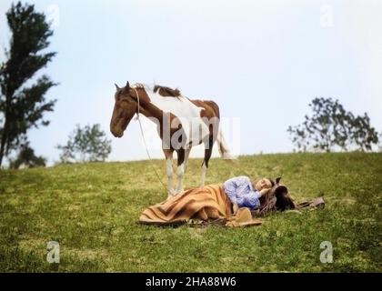 1920S MANN COWBOYKOPF, DER SICH AUF DEM SATTEL AUSRUHTE UND AUF DEN WESTERN PLAINS SCHLIEF, SEIN AMERIKANISCHES MALERPFERD HUMPELTE IN DER NÄHE - H894C HAR001 HARS FULL-LENGTH PERSONS PLAINS SADDLE MÄNNCHEN RISKIEREN PONY WESTERN PROFESSION RUHENDE COWBOYS GESCHICKLICHKEIT TRÄUME BERUF FERTIGKEITEN SÄUGETIERE ERTRÖHNEN SICH ABENTEUER SEINE KARRIERE AUF DEN BERUFEN KONZEPTIONELLE NÄHE PINTO SÄUGETIER MITTLEREN ERWACHSENEN MITTLEREN ERWACHSENEN MANN ENTSPANNUNG REST KAUKASISCHEN ETHNIZITÄT HAR001 ALTMODISCH Stockfoto