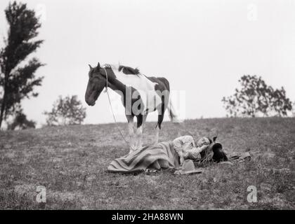 1920S MANN COWBOYKOPF, DER SICH AUF DEM SATTEL AUSRUHTE UND AUF DEN WESTERN PLAINS SCHLIEF, SEIN AMERIKANISCHES MALERPFERD HUMPELTE IN DER NÄHE - H894 HAR001 HARS SATTEL MÄNNCHEN PONY WESTERN PROFESSION B&W RUHE GESCHICK TRÄUME BERUF GESCHICK SÄUGETIERE ABENTEUER SEINE KARRIERE AUF DEM BERUFE KONZEPTIONELLE IN DER NÄHE PINTO SÄUGETIER MITTLEREN ERWACHSENEN MITTLEREN ERWACHSENEN MANN ENTSPANNUNG RUHE SCHWARZ-WEISS KAUKASISCHEN ETHNIZITÄT HAR001 ALTMODISCH Stockfoto