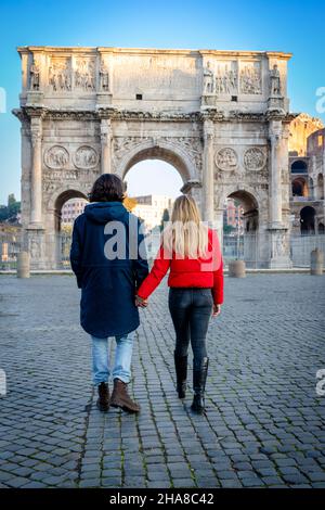 Junges Paar, das nach Rom reist. Das junge Paar hält sich die Hände und schlendert vor dem Titusbogen. Stockfoto