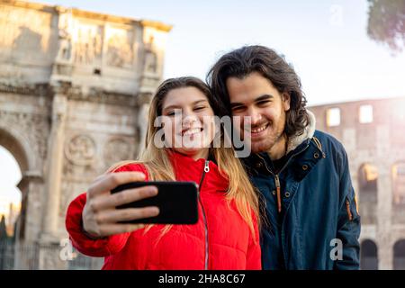 Sagen Sie Käse! Ein junges, charmantes Paar, das ein Selfie im historischen Zentrum Roms macht, in der Nähe des Titusbogens. Stockfoto