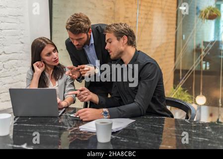 Selbstbewusster Manager, der seinen Kollegen Ideen auf einem Tablet präsentiert Stockfoto