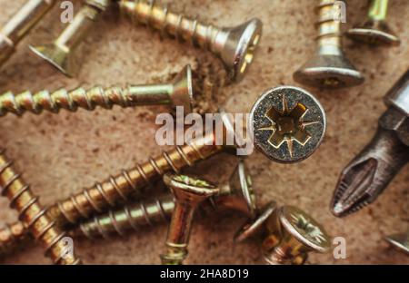 Schraube. Die Schrauben sind in einem Nahaufnahbsplan über die Holzoberfläche verstreut Stockfoto