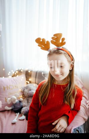 Mädchen in einem weihnachtskostüm schmückt den weihnachtsbaum Stockfoto