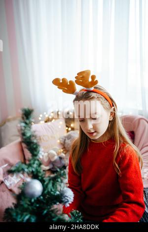 Mädchen in einem weihnachtskostüm schmückt den weihnachtsbaum Stockfoto