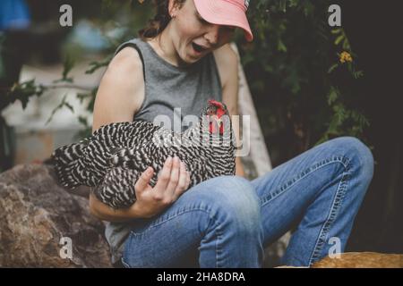 Happy teen Mädchen mit Huhn auf ihrem Schoß liegen Stockfoto