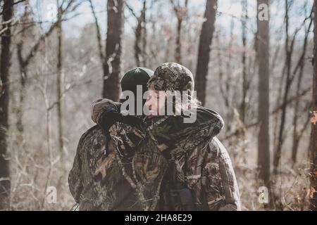 Vater und Sohn Hirsch Jäger umarmt in Wäldern Stockfoto