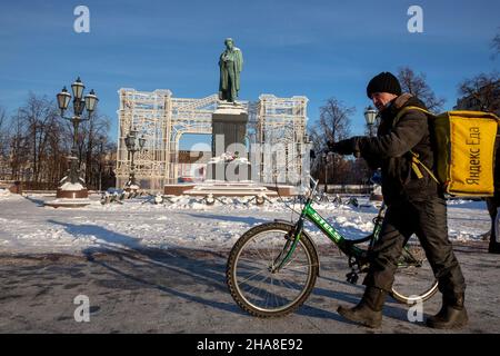 Moskau, Russland. 11th. Dezember 2021 Kurier des Lebensmittellieferdienstes "Yandex EDA" trägt am Wintertag einen Auftrag an einen Kunden auf dem Puschkinskaja-Platz (Tverskaya-Straße) im Zentrum der Moskauer Stadt, Russland Stockfoto