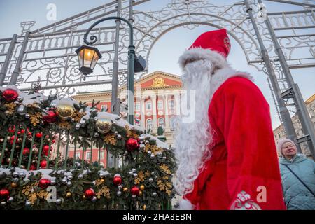 Moskau, Russland. 11th. Dezember 2021 Pater Frost (Russisch: DED Moroz) mit Gesichtsmaske begrüßt die Gäste auf der Messe der Reise zum Weihnachtswinterfest auf dem Tverskaya-Platz im Zentrum von Moskau, Russland Stockfoto