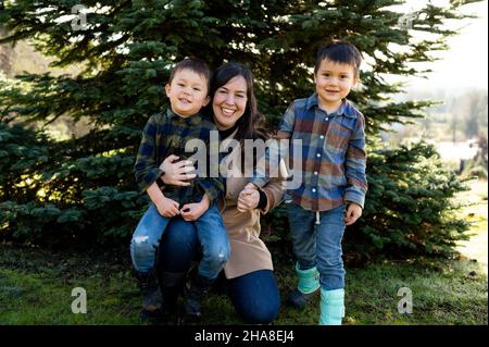 Glückliche Mutter mit Jungs vor dem weihnachtsbaum auf der Farm Stockfoto