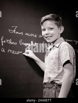 1940S LÄCHELNDER SCHULJUNGE AN DER TAFEL, DER DIE GETTYVSBURG-ADRESSE AUSSCHREIBT KAMERA ANSCHAUT - S1256 HAR001 HARS VERTRAUEN S B&W BLICKKONTAKT FREIHEIT SCHULEN GRAD GLÜCK ADRESSE FRÖHLICHES WISSEN STOLZ PRIMARY LÄCHELN FREUDVOLLES SCHULWACHSTUM JUGENDLICHE PRE-TEEN PRE-TEEN JUNGE SCHWARZ-WEISS KAUKASISCHE ETHNIE HAR001 ALTMODISCH Stockfoto