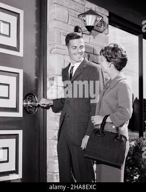 1960S JUNGE PAAR VOR DER TÜR EINES NEUEN MODERNEN HAUSMANNS AUS DER MITTE DES JAHRHUNDERTS LÄCHELN FRAU AN, WÄHREND SIE DIE TÜR ZU ÖFFNEN IHR NEUES ZUHAUSE - S14217 HAR001 HARS STIL WILLKOMMEN LACHEN TEAMWORK DESIGN ZUFRIEDEN FREUDE LIFESTYLE ZUFRIEDENHEIT ARCHITEKTUR FRAUEN HÄUSER VERHEIRATET EHEPARTNER EHEMÄNNER MODERNES HEIM LEBEN KOPIEREN RAUM FREUNDSCHAFT HALBE LÄNGE DAMEN PERSONEN WOHN MÄNNER GEBÄUDE VERTRAUEN AUSDRÜCKE B & W PARTNER ZIELE TRÄUME STRUKTUR GLÜCK FRÖHLICH AUFREGUNG AUSSEN NIEDRIGEN WINKEL STOLZ HÄUSER LÄCHELT FREUDIGE RESIDENZ HAUSBESITZER MITTLEREN ERWACHSENEN MITTLEREN ERWACHSENEN MANN MITTLEREN ERWACHSENEN FRAU ZWEISAMKEIT ENTSPERREN FRAUEN Stockfoto